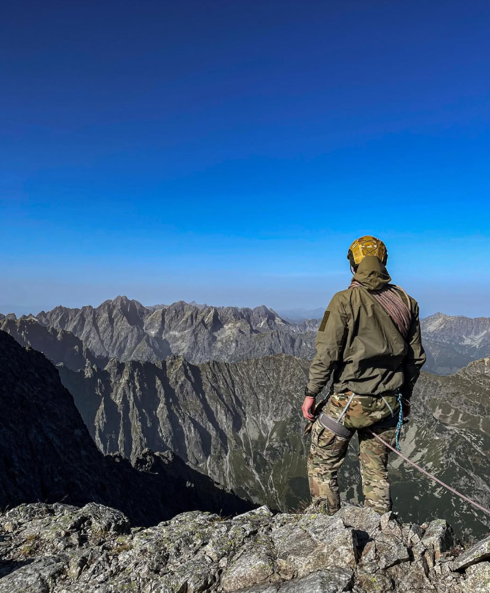 Climber looking across rugged mountain peaks from a rocky summit