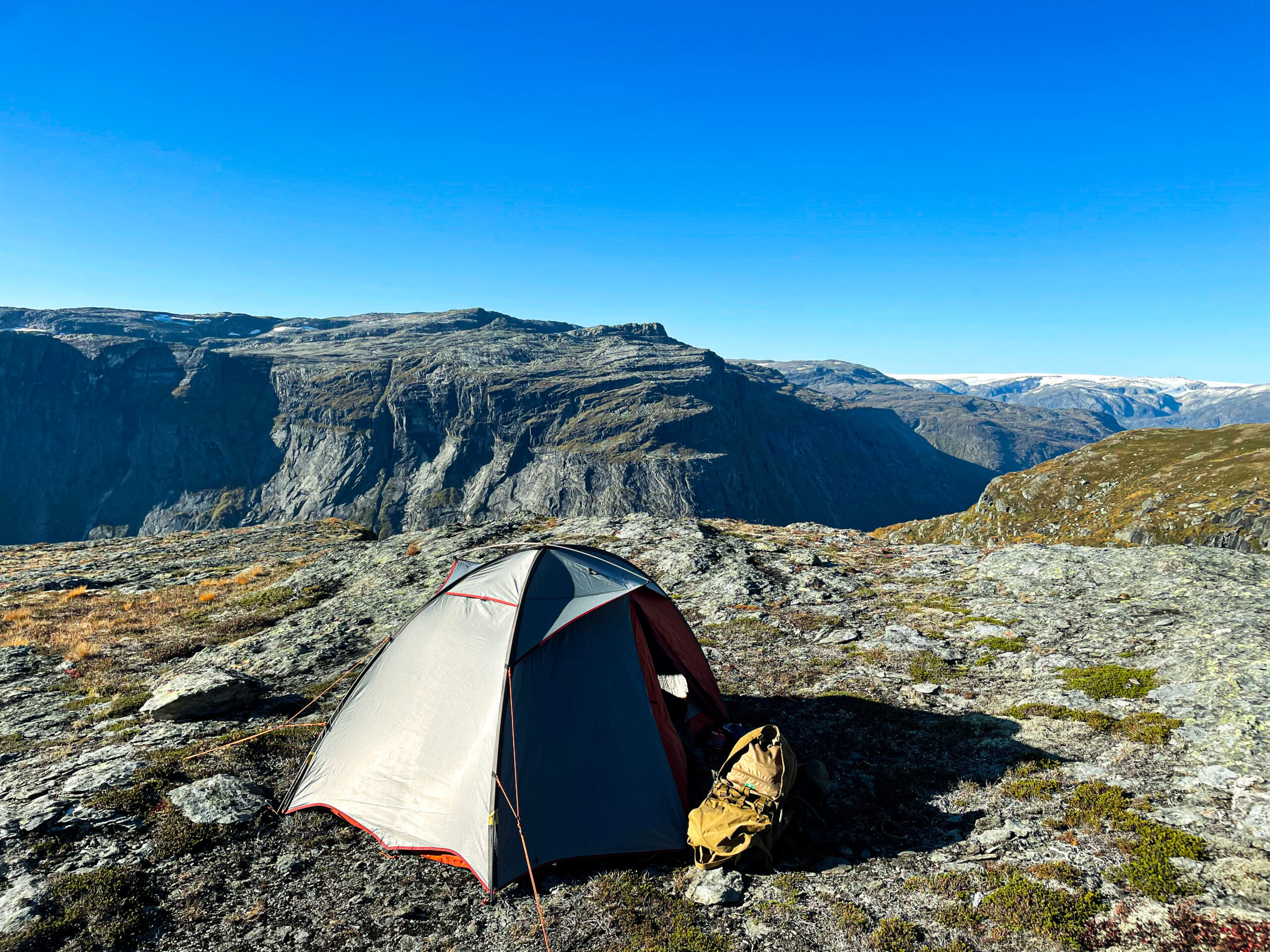 Tent and backpack on a rocky plateau above a mountain valley