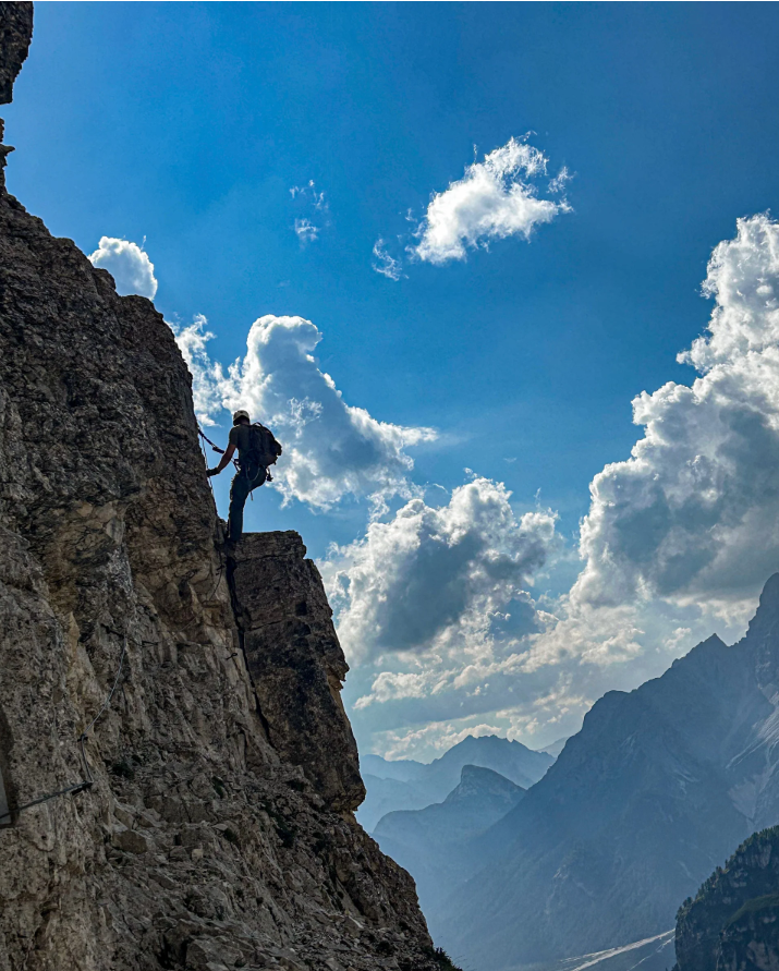 Climber silhouetted on a limestone face against a blue sky and distant mountains